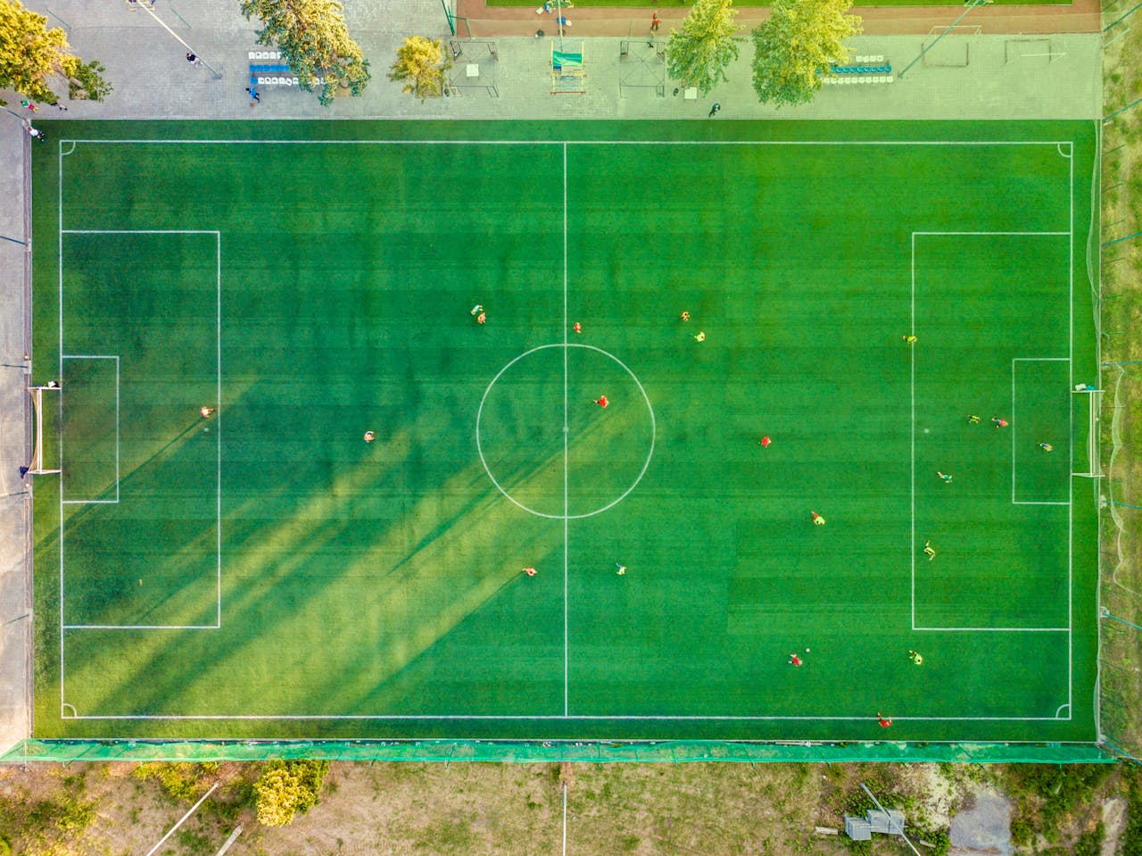 Home Aerial shot of a soccer game with players on a vibrant green field.
